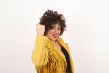 Sevinçten havalara uçmuş mutlu, sevinçli bir kadın, iyi haberler aldığına sevinmiş, mutluluktan hareketler yapmış, yumruğunu sıkmış ve kazanan bir jest yapmış. Tepki konsepti.