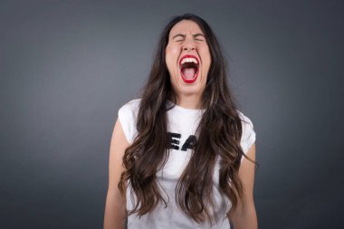 Gri arka planda bağıran güzel kadın.  