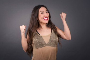 Kutlama yapan yumruklu güzel bir kadın Gri arka planda duruyor. 