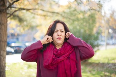 Güzel orta yaşlı kadın Arap, parkta kulaklarını kapatıyor.  