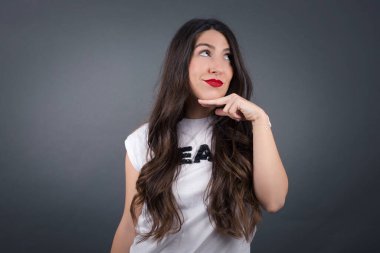 Gri arka planda düşünen güzel bir kadın.  