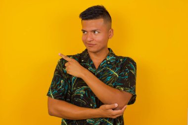 Kamerada poz veren genç bir İspanyol 'un portresi hileli bir bakış ve yana hareket. Erkek tasarımcı güzel ürünleri işaret parmağıyla sunuyor. Hareket kavramı.