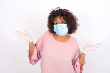 Yüz maskesi takan ve günlük kıyafet giyen kadın beyaz stüdyo arka planında izole edilmiş.