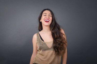 Güzel bir kadın gülüyor Gri arka planda duruyor. 