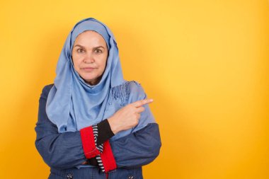 Heyecanlı orta yaşlı Müslüman kadın tesettür noktalarında mutlu bir şekilde arka plandaki kopya boşluğunda 