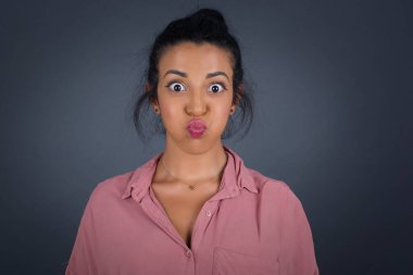 Komik yüzlü, güzel, genç bir kadın. Havayla şişmiş ağız, çılgın bir ifade..