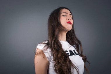 Güzel bir kadın gücendi. Gri arkaplanda duruyor. 