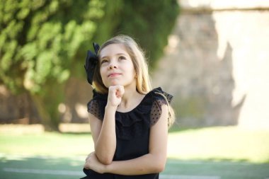 Düşünceli, gülümseyen bir kızın portresi elini çenesinin altında tutar, yan bakar, ilginç bir şey düşünür ya da merak eder, sıradan giyinir.