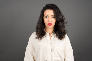 Gri arka planda gelişigüzel giyinmiş güzel esmer kadın..  