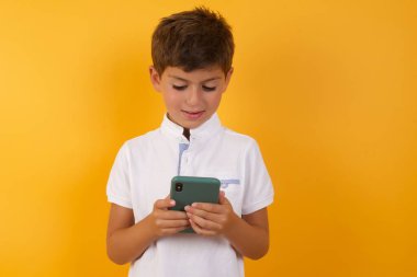 Sarı duvarda akıllı telefonu olan sevimli çocuk.  