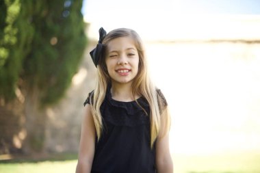 Sevimli sarışın kız mutlu bir ifadeyle gözlerini kırpıyor. Yüz ifadeleri ve insanların duygu konsepti.