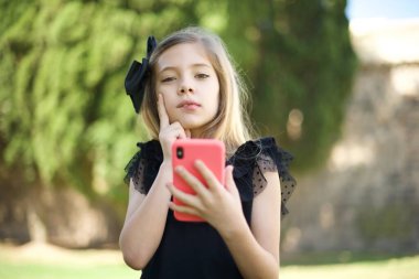 Düşünen, siyah elbiseli ve cep telefonu kullanan güzel bir kızın görüntüsü..