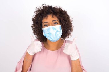 Yüz maskesi takan bir kadın ve beyaz stüdyo arka planında izole edilmiş sıradan giyinen bir kadın.