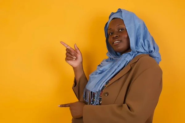 Позитивная Привлекательная Молодая Афроамериканская Мусульманка Указывает Сторону Веселым Удивленным Выражением — стоковое фото
