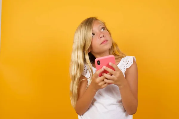 Linda Chica Pensante Con Teléfono Inteligente Mirando Hacia Otro Lado — Foto de Stock