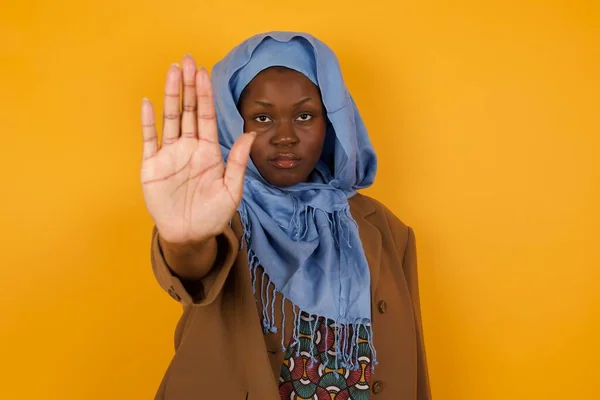 Young beautiful caucasian woman doing stop gesture with palm of the hand. Warning expression with negative and serious gesture on the face isolated over gray background.