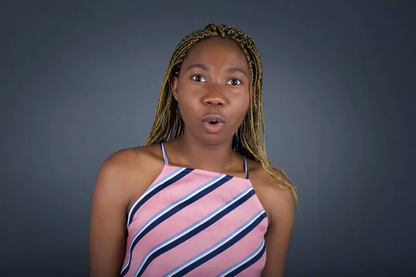 驚いた若いアフリカ系アメリカ人女性は ショックを受けた外観でカメラを見つめながら灰色の背景の上に — ストック写真