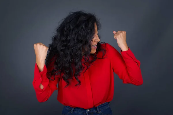 Kıvırcık Saçlı Kırmızı Tişörtlü Esmer Kadın Başarısını Zaferini Kutluyor Yumruklarını — Stok fotoğraf