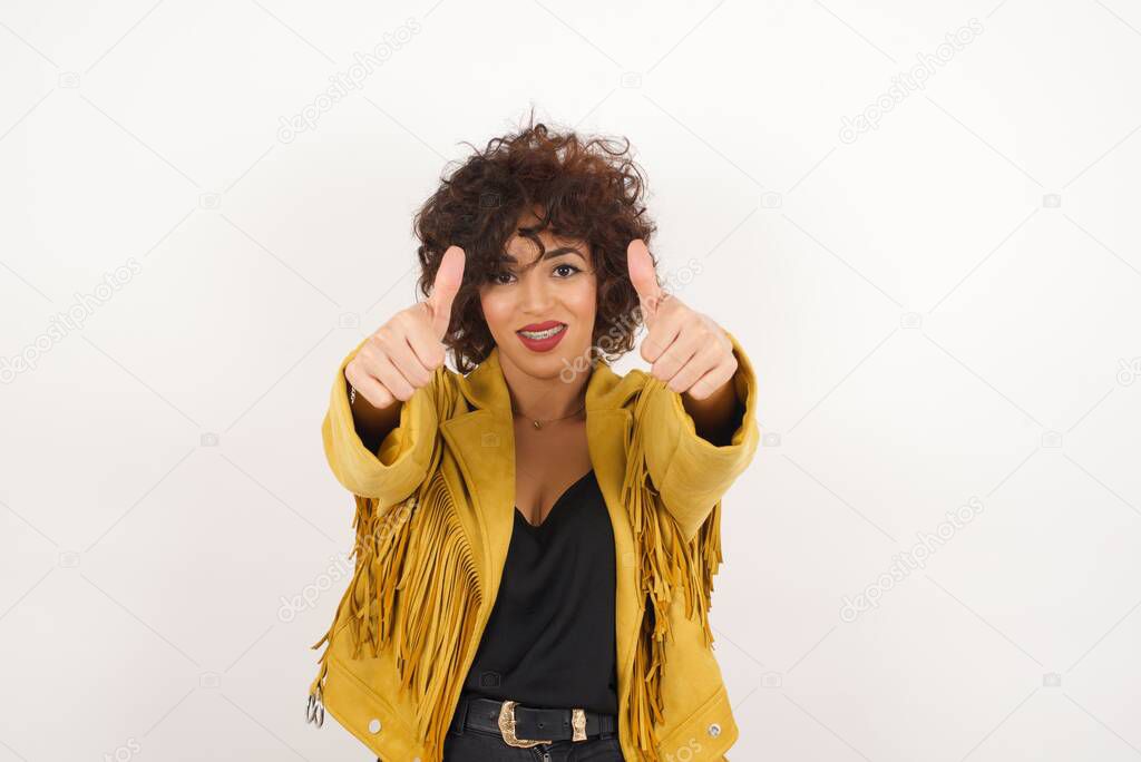 Beautiful  woman in suede jacket showing thumbs up   studio shot
