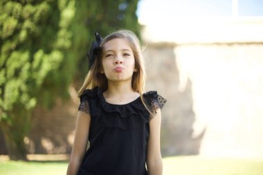 Hoş görünümlü genç bir kız birini öpecek gibi dudaklarını tutuyor, mutlu bir ifadesi var, suratsız surat. Dışarıda dikiliyorum. Güzellik konsepti.