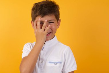 Yüzü sarı duvara dönük gülümseyen sevimli çocuk.  