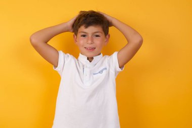 Sarı duvarın arkasında elleri olan sevimli bir çocuk.  