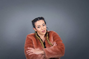 Güzel, kendine güvenen, çapraz kollu, şık kıyafetler giymiş, stüdyoda poz veren genç bir kadının belden yukarı pozu..