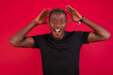 Yakışıklı Afro-Amerikan bir adamın portresi kameraya heyecanla bakıyor, ellerini başının üstüne kaldırıyor, beklenmedik bir şey fark ediyor, duvarın arkasında izole edilmiş. Sevimli adam ani haberlere tepki verir..