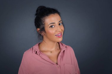 Gri stüdyo arka planına zımparalarken gülümseyen ve kameraya bakan güzel bir kız..