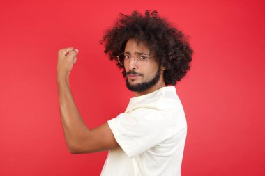 Kızıl duvarda kas gösteren afro saçlı genç bir adam. 