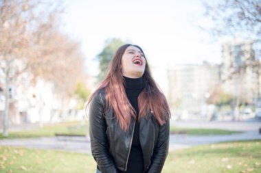 Genç ve güzel bir kadın parkta gülüyor.