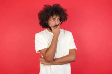 Kızıl duvara karşı düşünen afro saçlı genç bir adam. 