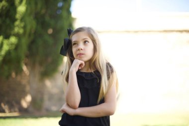 Siyah elbiseli düşünceli tatlı bir kızın portresi elini çenesinin altında tutuyor, bir şey hatırlamaya çalışıyor ya da ilgi çekici bir şey dinliyor, sıradan giyinmiş, içeride poz veriyor. Gençlik kavramı.