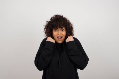 Kafkasyalı genç kadın başarısını ve zaferini kutluyor yumruklarını neşeyle sıkıyor. Hedefine ve amaçlarına ulaşmaktan mutlu olan şapkalı şanslı kadın. Pozitif duygular, duygular..