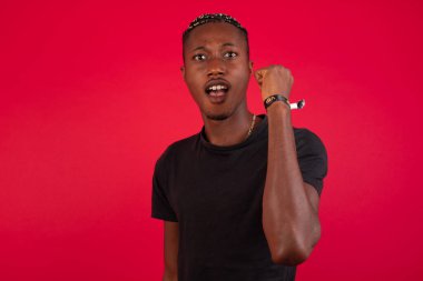 Sevinçten havalara uçmuş mutlu Afro-Amerikan erkeği iyi haberler aldığına seviniyor, mutluluktan hareketler yapıyor, yumruğunu sıkıyor ve kazanan jestler yapıyor. Tepki konsepti.