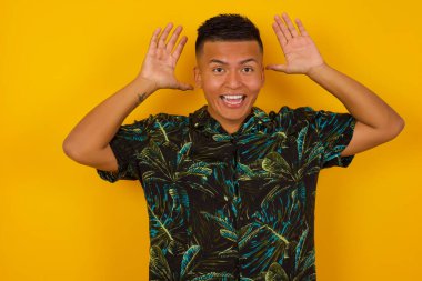 Yakışıklı İspanyol erkeğin portresi, kameraya heyecanla bakıyor, ellerini başının üstünde tutuyor, beklenmedik bir şey fark ediyor, duvarın üstünde izole edilmiş. Sevimli adam ani haberlere tepki verir..