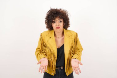 Kafası karışmış, kolları açık genç bir kadın omuzlarını silkip 