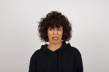 Vücut dili. Gri duvara karşı poz veren, suratını asan, bir şeyden tiksindiğini gösteren, stresli, güzel bir kız..