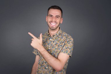 Yakışıklı sarışın beyaz adam, gri arka planda dikilirken sana gülümsüyor..