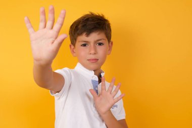 Sarı duvarda duran sevimli çocuk.  