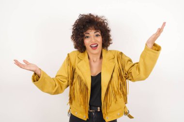Neşeli kadın hoş bir jest yapıyor. Beyaz arka planda yalnız başına kollarını havaya kaldırıyor..