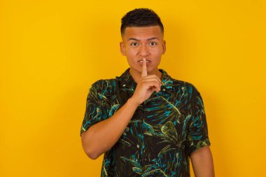 Sırrımı söyleme ya da yüksek sesle konuşma, lütfen! Duygusal olarak şaşırmış İspanyol bir adam sessiz ol diyor, sessiz ol, korkmuş bir yüz ifadesi var sırrını açıklamaktan korkuyor, gri stüdyo duvarına karşı duruyor..