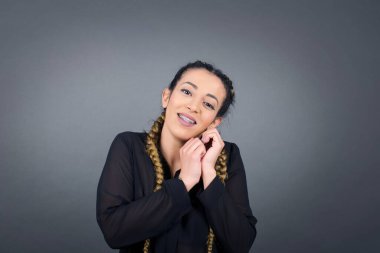 Tatlı yüzlü, rüya gibi, genç bir bayan. Ellerini yüzünün yanında çapraz tutuyor. Hoş bir şey için heyecanlanıyor..