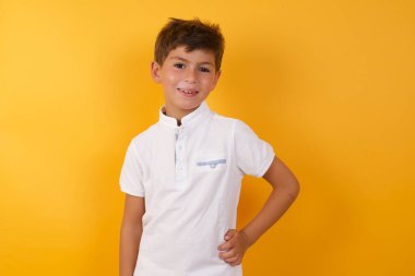 Sarı duvara gülümseyen sevimli çocuk.  