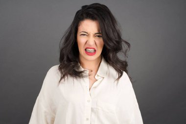 Gündelik giyinmiş güzel esmer kadın gri arka plandan tiksiniyor..  