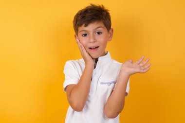 Sarı duvara yaslanmış kafası karışık şirin bir çocuk.  