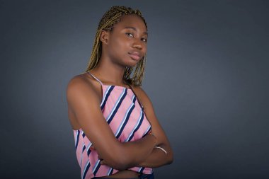 Güzel, genç, Afro-Amerikan bir kadının kolları bağlı bir şekilde evde duruşu. Kameraya bakıp gülümsüyor. Kendine güvenen kız..