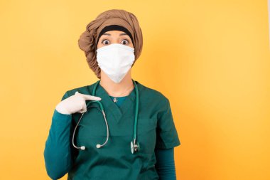 Şaşırmış güzel doktor kadın sersemlemiş durumda, şaşkın bir şekilde kendini parmağıyla işaret ederek 