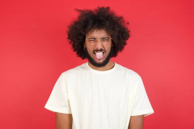 Kızıl duvarda dili olan afro saçlı genç bir adam. 