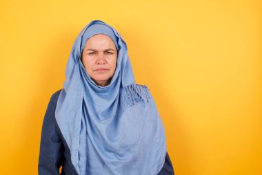Öfkeli orta yaşlı Müslüman kadının portresi tesettürlü kaşlarını çatarak bir şeyden hoşnutsuz..
